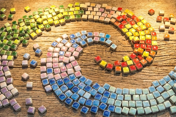 Mini-Mosaiksteine in Spiralform gelegt, farbige Keramik-Tesserae auf Holzuntergrund | Der Römer Shop